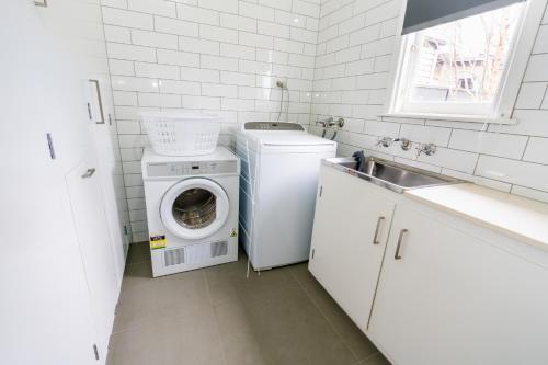 a white laundry room with a washing machine and a sink at Sovereign Park Motor Inn in Ballarat