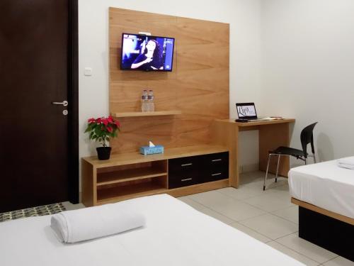 1 dormitorio con escritorio y TV en la pared en LN9 Bandung Guest House en Bandung