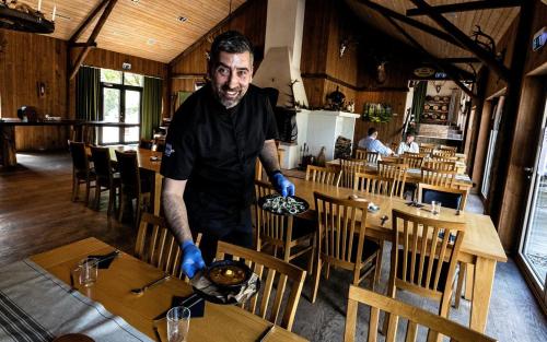 a man in a restaurant preparing food on a table at Ulvereds Hjorthägn - Camp Mayfly in Ulvered