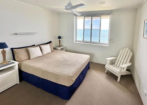 a bedroom with a bed and a chair and a window at Craigmore Penthouse in Yamba