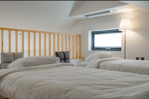 drie bedden in een kamer met een raam bij Jois House in Jeju-stad