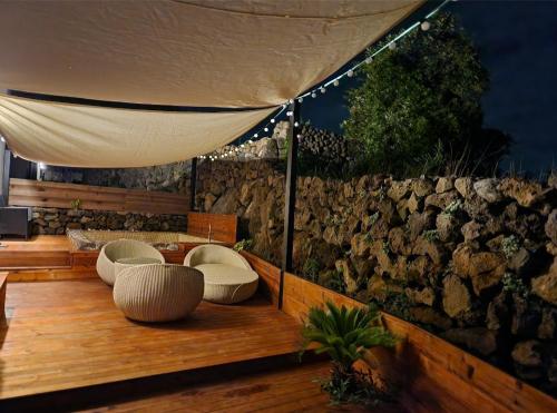 eine Terrasse mit Stühlen und einer Steinmauer in der Unterkunft Jois House in Jeju-do