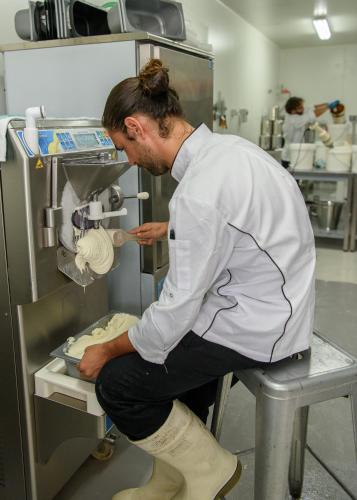 a man in a kitchen preparing food in a machine at Bodalla Dairy Shed Guest Rooms in Bodalla