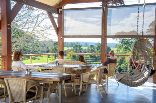 a group of people sitting at tables on a porch at Bodalla Dairy Shed Guest Rooms in Bodalla