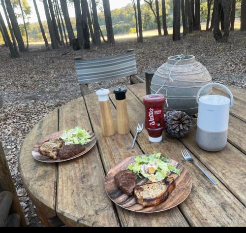 una mesa de madera con dos platos de comida. en Eversprings Glamping, en Mount Helena