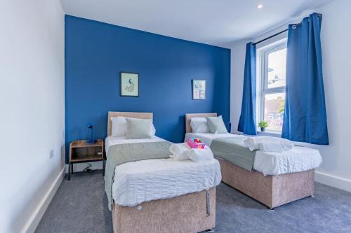 Charming 3 BR in Folkestone! في فولكستون: غرفة نوم بسريرين وجدار ازرق