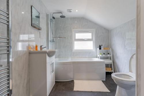 a white bathroom with a tub and a toilet at Charming 3 BR in Folkestone! in Folkestone