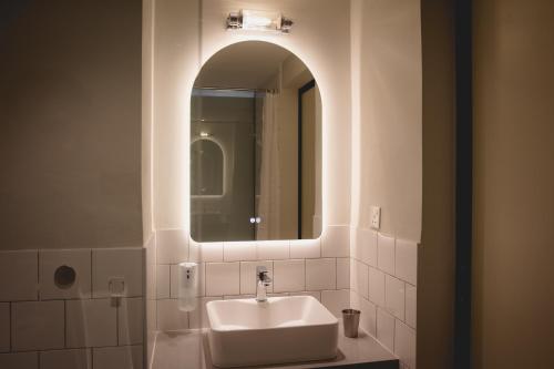 a white bathroom with a sink and a mirror at Hotel Mokozoyo in George Town