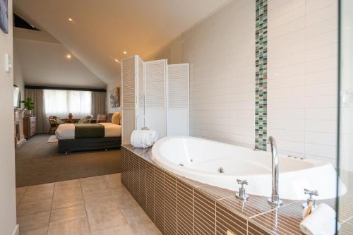 a bathroom with a bath tub and a bedroom at Prideau's of Margaret River in Margaret River Town
