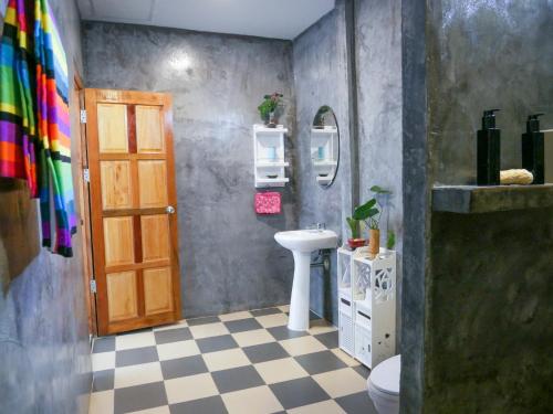 a bathroom with a sink and a toilet and a door at Enda Lanta Bungalows in Ko Lanta