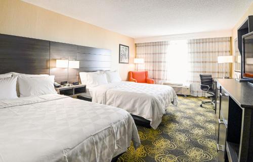 a hotel room with two beds and a chair at Holiday Inn University Area Charlottesville by IHG in Charlottesville