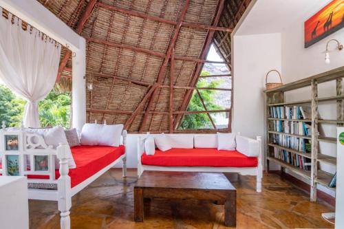 a living room with a red couch and a large window at Minimi Couzy villa casaurina in Malindi