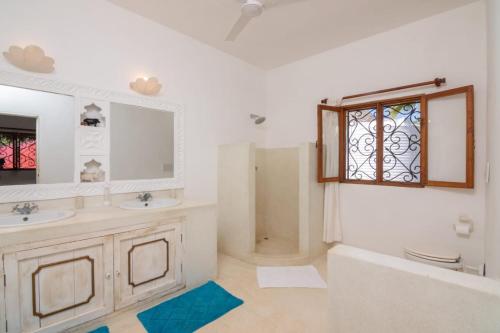 un bagno con due lavandini, una doccia e una finestra di Minimi Couzy villa casaurina a Malindi