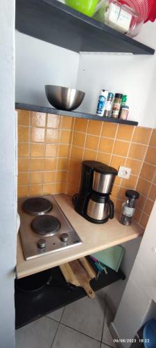 - une cuisine avec une cuisinière et une cafetière sur une étagère dans l'établissement Petit Studio simple au bord des plages, à La Ciotat
