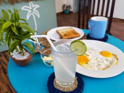 un tavolo blu con un piatto di cibo e un bicchiere di latte di The Calm Palm a Hikkaduwa