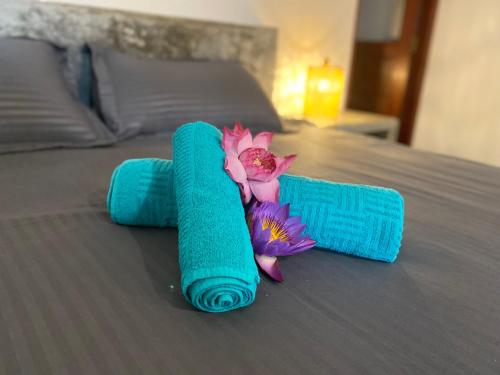 a blue rolled up towel with a flower on a bed at The Calm Palm in Hikkaduwa