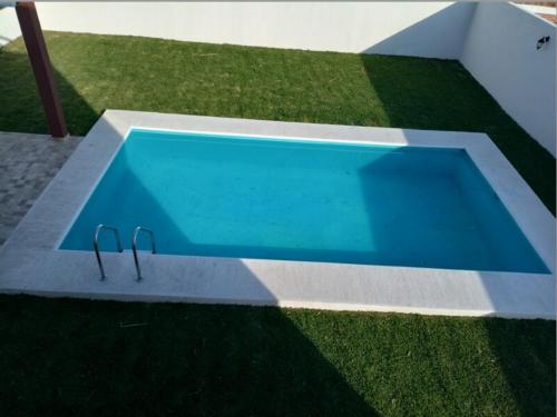 a swimming pool with a pair of shoes in the grass at Alquiler de Hermosa Casa sola con Piscina Privada in Los Limones
