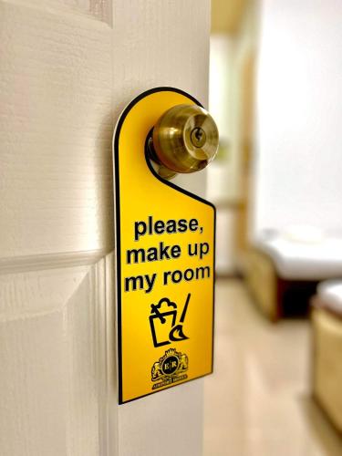 a yellow doorhandle with a sign that says please make up my room at E&R Airport Hotel in Dumaguete