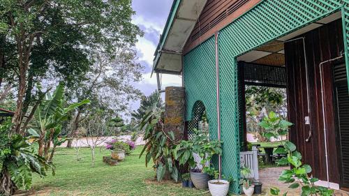 a green building with potted plants outside of it at Aaira 8Pari Riverview Lodge in Kota Bharu