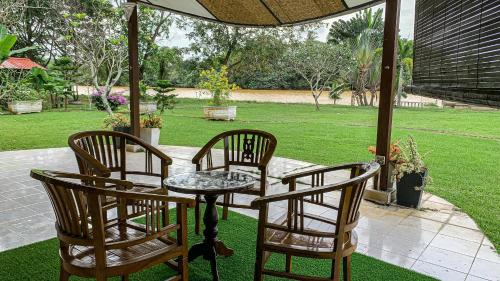 two chairs and a table and two tables and chairs at Aaira 8Pari Riverview Lodge in Kota Bharu