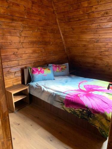 a bed in a room with a wooden wall at Cabana Bravak One in Firiza-de-Jos