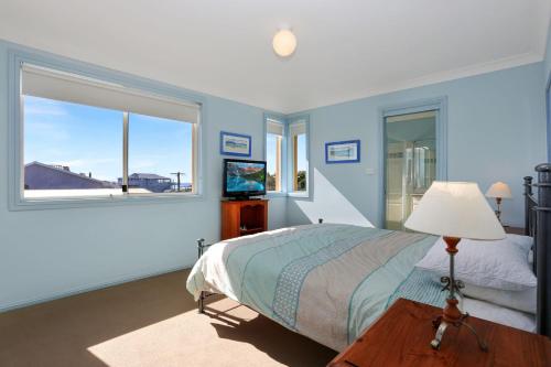 a blue bedroom with a bed and a window at Aquarius Apartment 7 in Hawks Nest