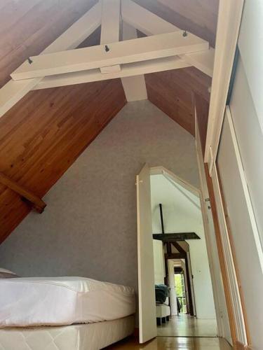 Cette chambre mansardée comprend un lit et un plafond en bois. dans l'établissement Maison normande sur parc arboré ambiance bucolique, à La Gonfrière