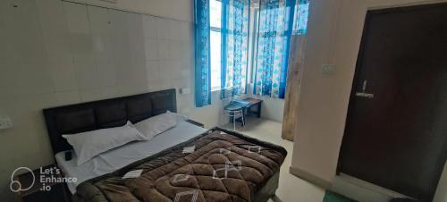 um quarto com uma cama e uma janela em Apna Guest House Dehradun em Dehradun