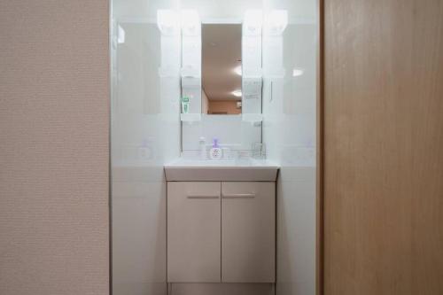 a white bathroom with a sink and a mirror at ダイヤモンド悠 大山店 in Tokyo