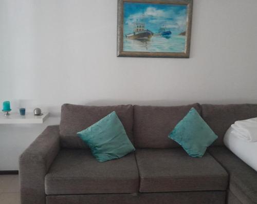 a brown couch with two blue pillows in a living room at Small apartment by the beach in Sesimbra