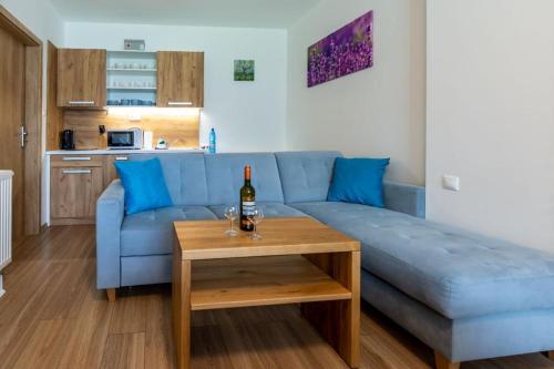 a living room with a blue couch and a table with a bottle of wine at Apartmán Mirka in Liptovský Ján