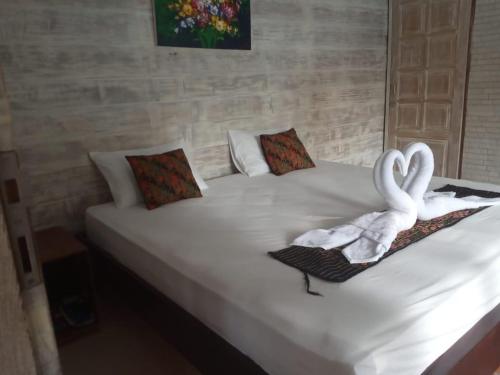 zwei Schwäne sitzen auf einem weißen Bett in der Unterkunft Villa Almond Mayo in Gili Trawangan