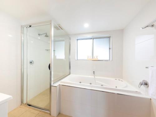 a white bathroom with a tub and a shower at NRMA Forster Tuncurry in Tuncurry