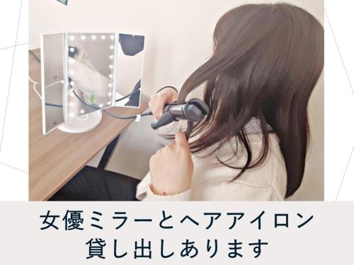 a woman dries her hair with a hair dryer at Hotel Meldia Shijo Kawaramachi Annex in Kyoto