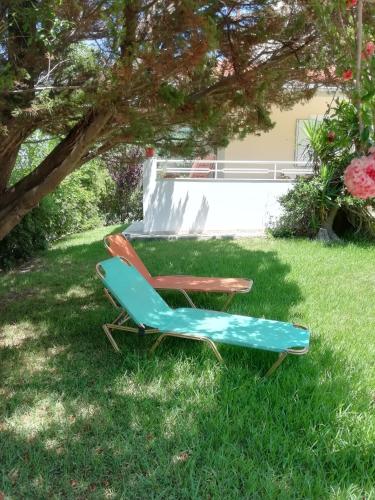 a lawn chair and a lounge chair under a tree at Sea and Stars House in Svoronata