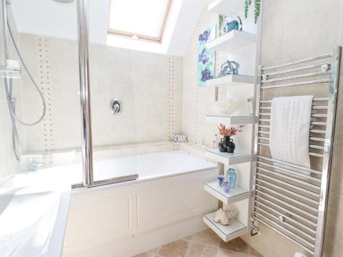 a white bathroom with a tub and a shower at Ocean Blue in Carbis Bay