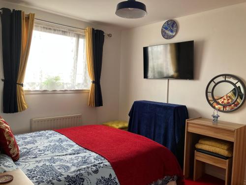 1 dormitorio con 1 cama con manta roja y ventana en Dundee City Waterfront, 2 Bedroom 2 Bathroom Apartment - short walk to V and A, Bus & Train Stations, en Dundee