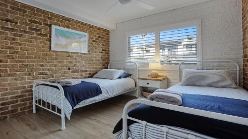 two beds in a room with a brick wall at unit 6 53 Ocean Drive, Merimbula in Merimbula