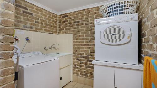 a bathroom with a washer and dryer next to a brick wall at unit 6 53 Ocean Drive, Merimbula in Merimbula
