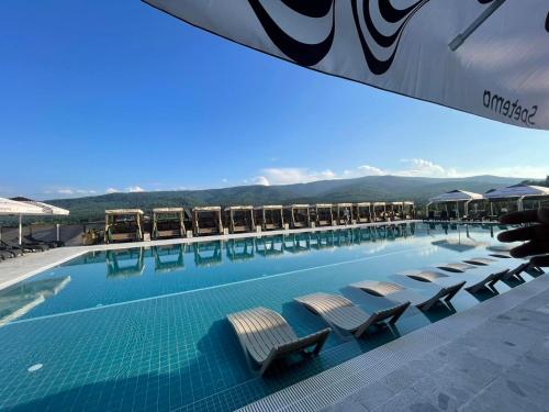 una piscina con sedie e montagne sullo sfondo di Grande Vista Resort & Spa a Tsigov Chark