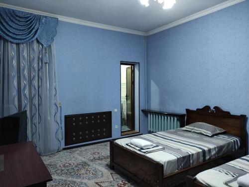 - une chambre bleue avec un lit et une fenêtre dans l'établissement REAL Tashkent, à Tachkent