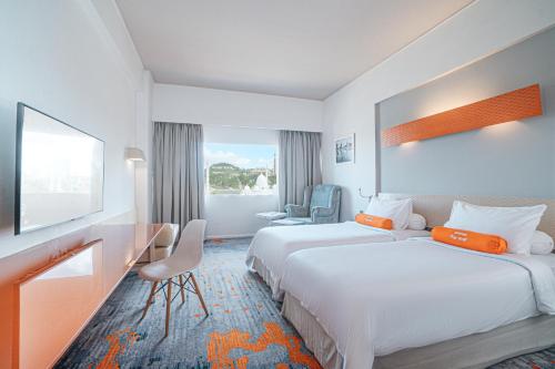 a hotel room with two beds and a desk at HARRIS Hotel Batam Center in Batam Center