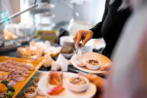 a woman is serving food in a buffet at Bio-Seehotel Zeulenroda in Zeulenroda
