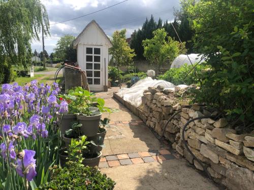 un jardín con flores púrpuras y una pared de piedra en A 10mn de VICHY studio dans ancienne ferme, en Vichy