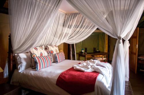 a bedroom with a canopy bed with white curtains at Monate Game Lodge in Modimolle
