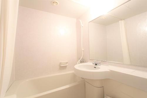 a white bathroom with a sink and a bath tub at KOKO HOTEL Sendai Station West in Sendai