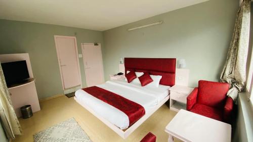 a bedroom with a red bed and a red chair at The View Meadow in Manāli