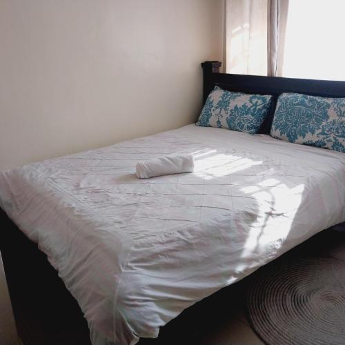 uma cama grande com lençóis brancos e almofadas azuis em Iona suits em Nairobi