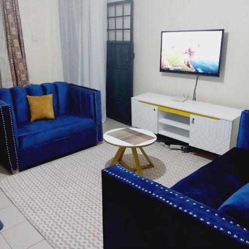 uma sala de estar com duas cadeiras azuis e uma televisão em Iona suits em Nairobi