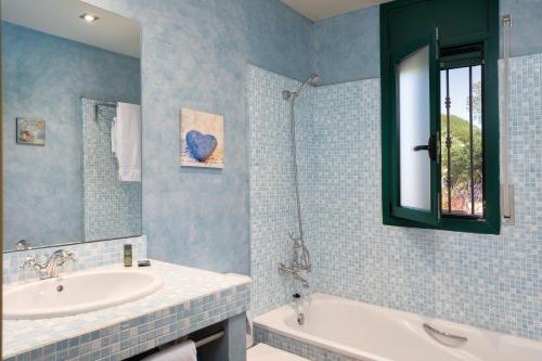 a blue tiled bathroom with a tub and a sink at Flateli Peralada in Peralada